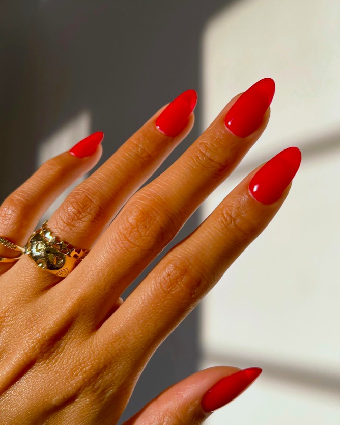 Bright red almond nails under sunlight