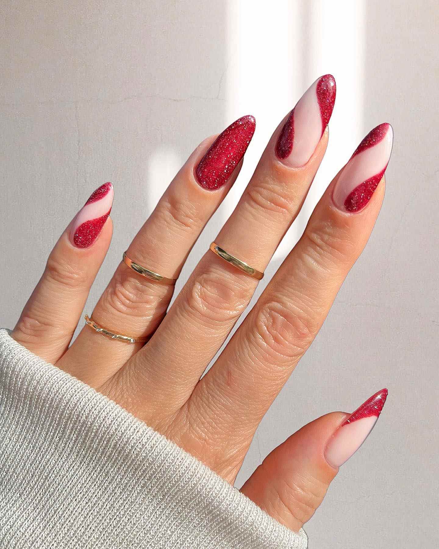 Swirling red glitter design on nude nails