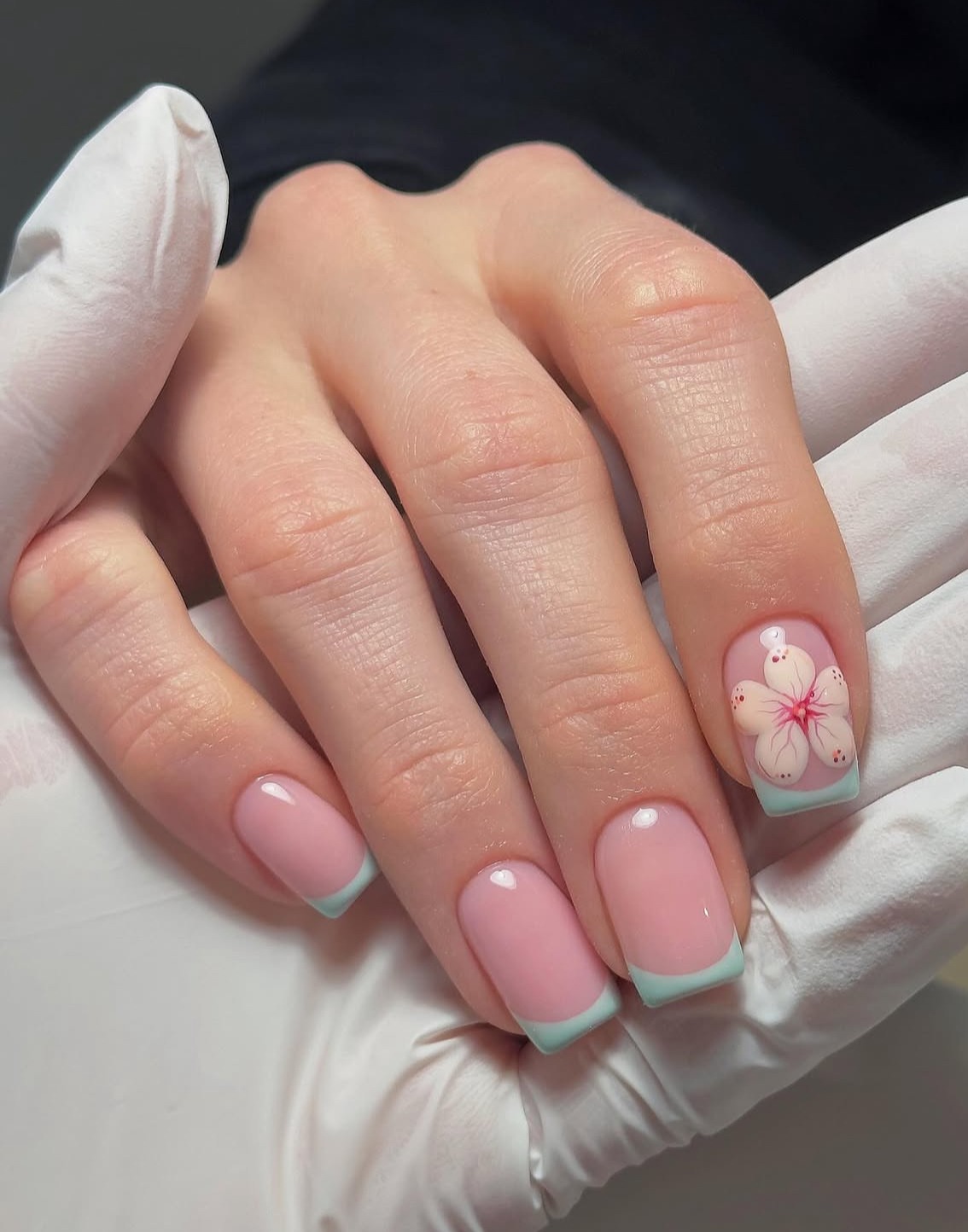 Pink nails with blue French tips and floral accent