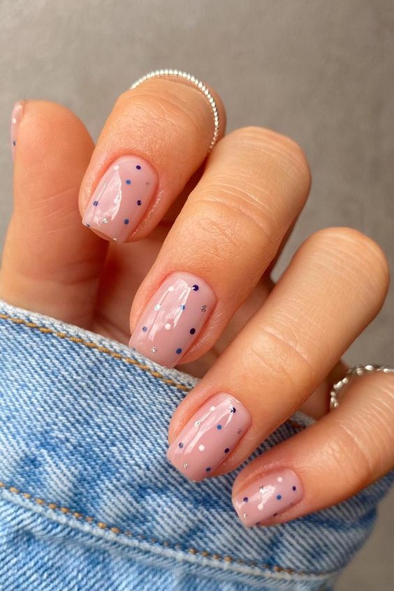 Nude nails with blue polka dots and sparkle