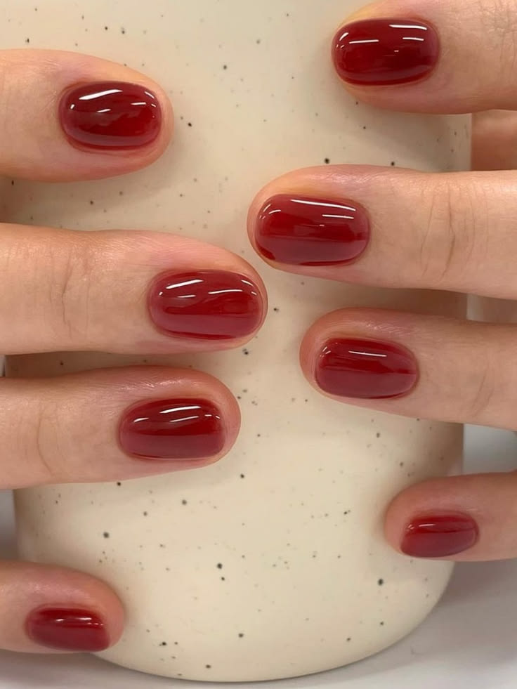 Bold red short almond gel nails with a glossy finish