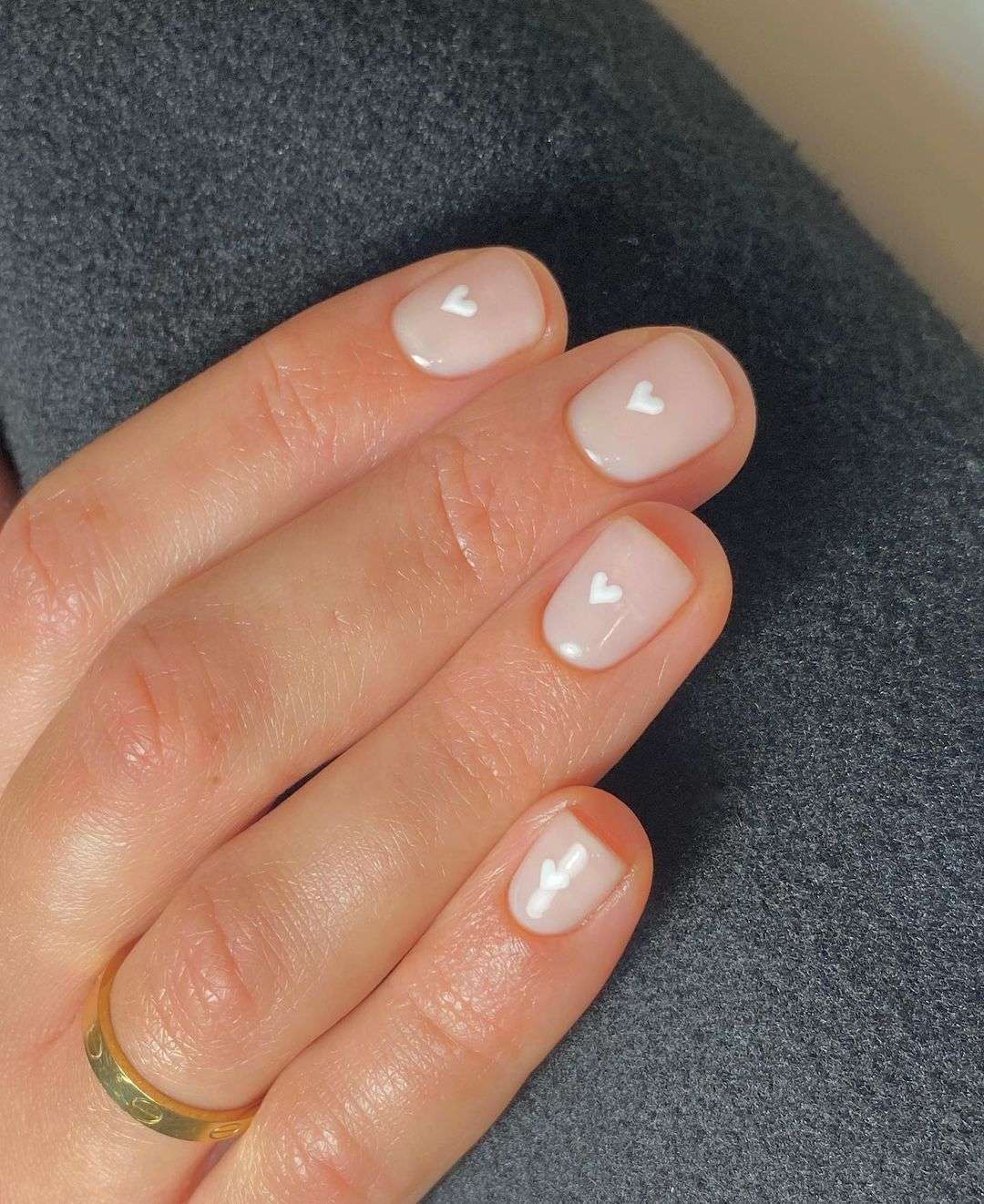 Short round gel nails with white heart accents on sheer base