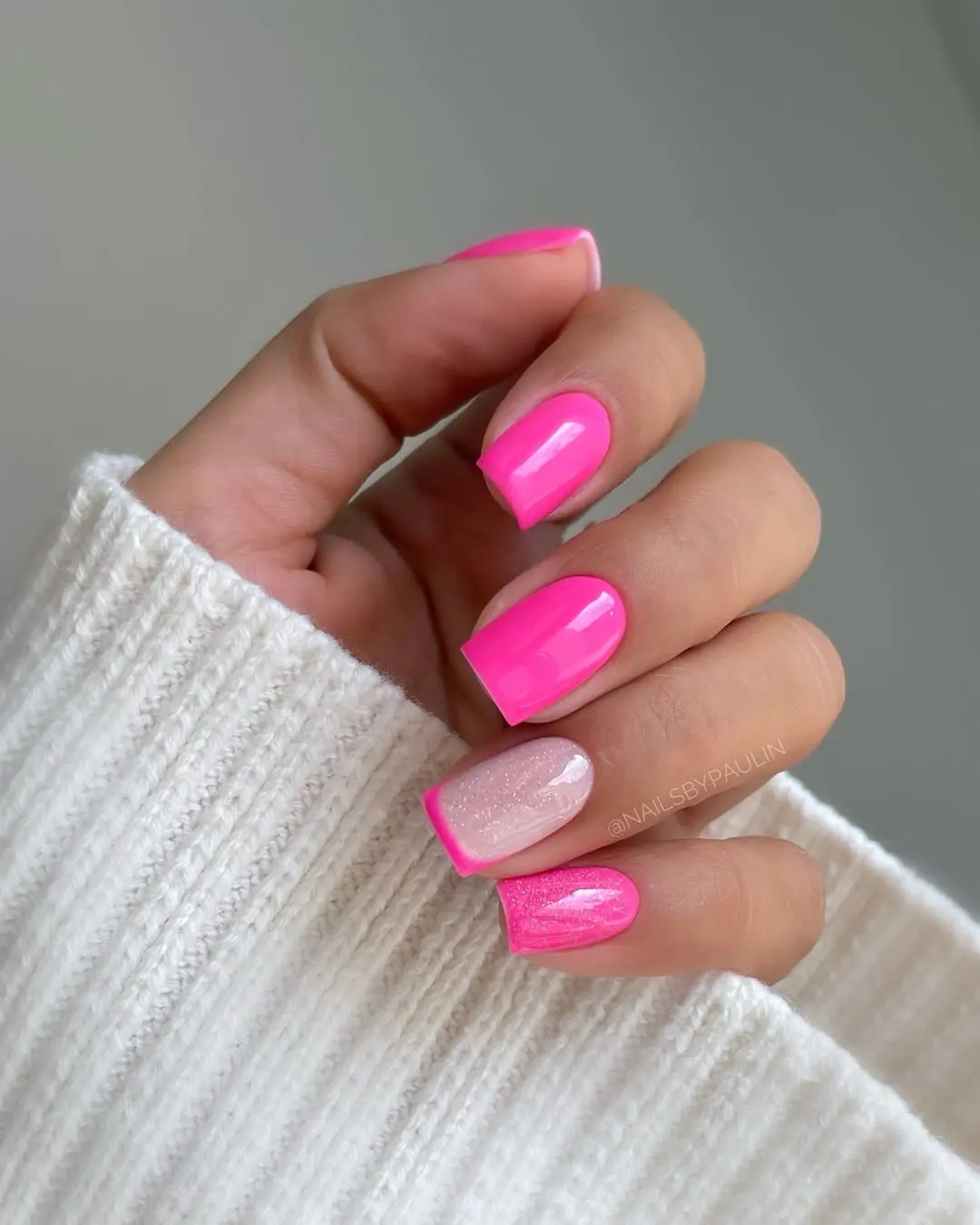Short square nails with neon pink and shimmer accent, bold nail trend.