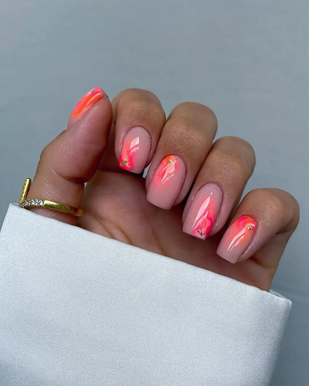 Short square nails with coral splash and jewel accents, trendy nail design.