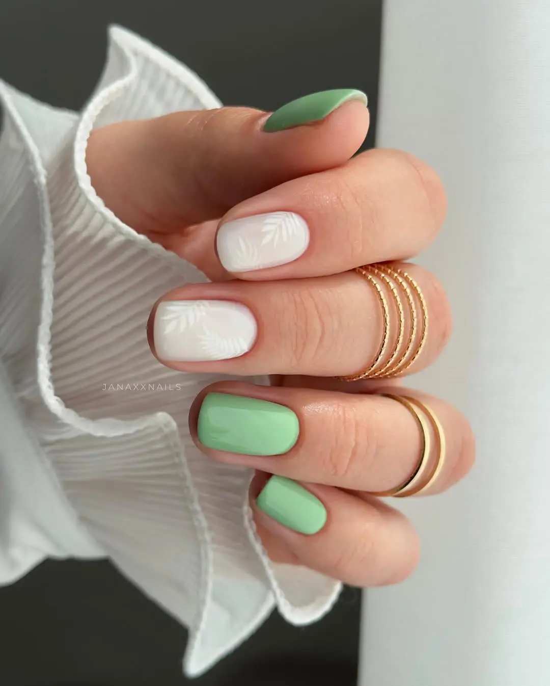 Short square nails with mint and white leaf design, fresh nail art.