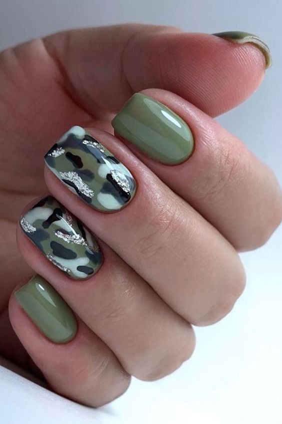 Short square nails with camouflage pattern and silver accents, edgy and modern.
