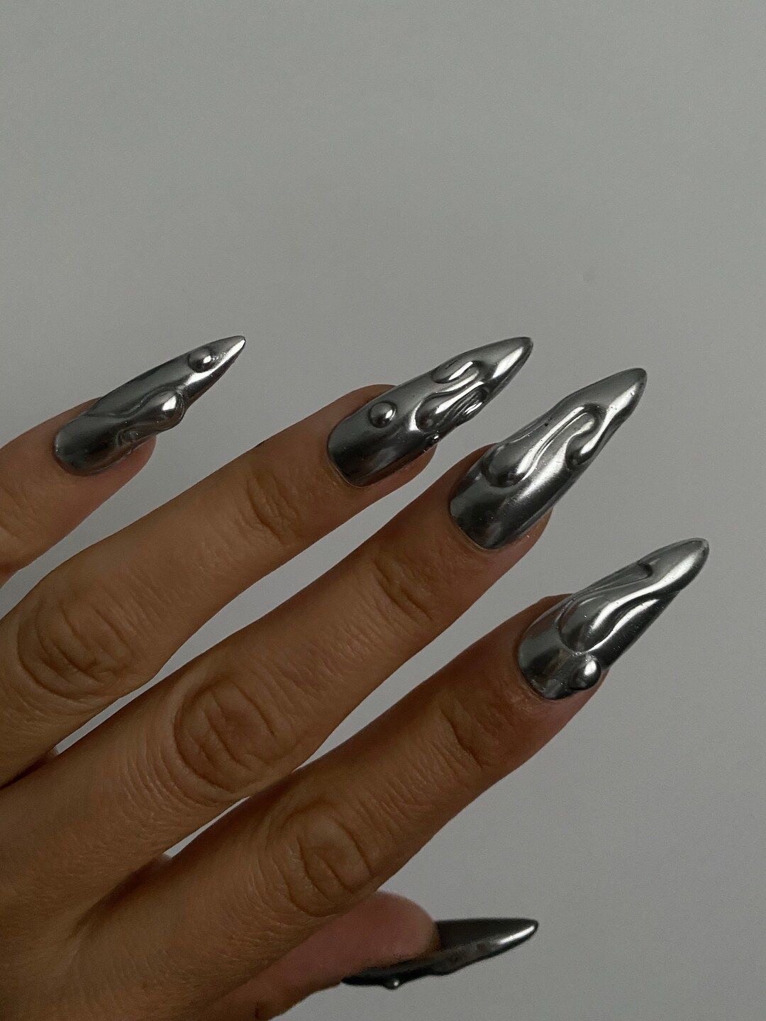 Stiletto nails with sculpted chrome design, artistic nail trend