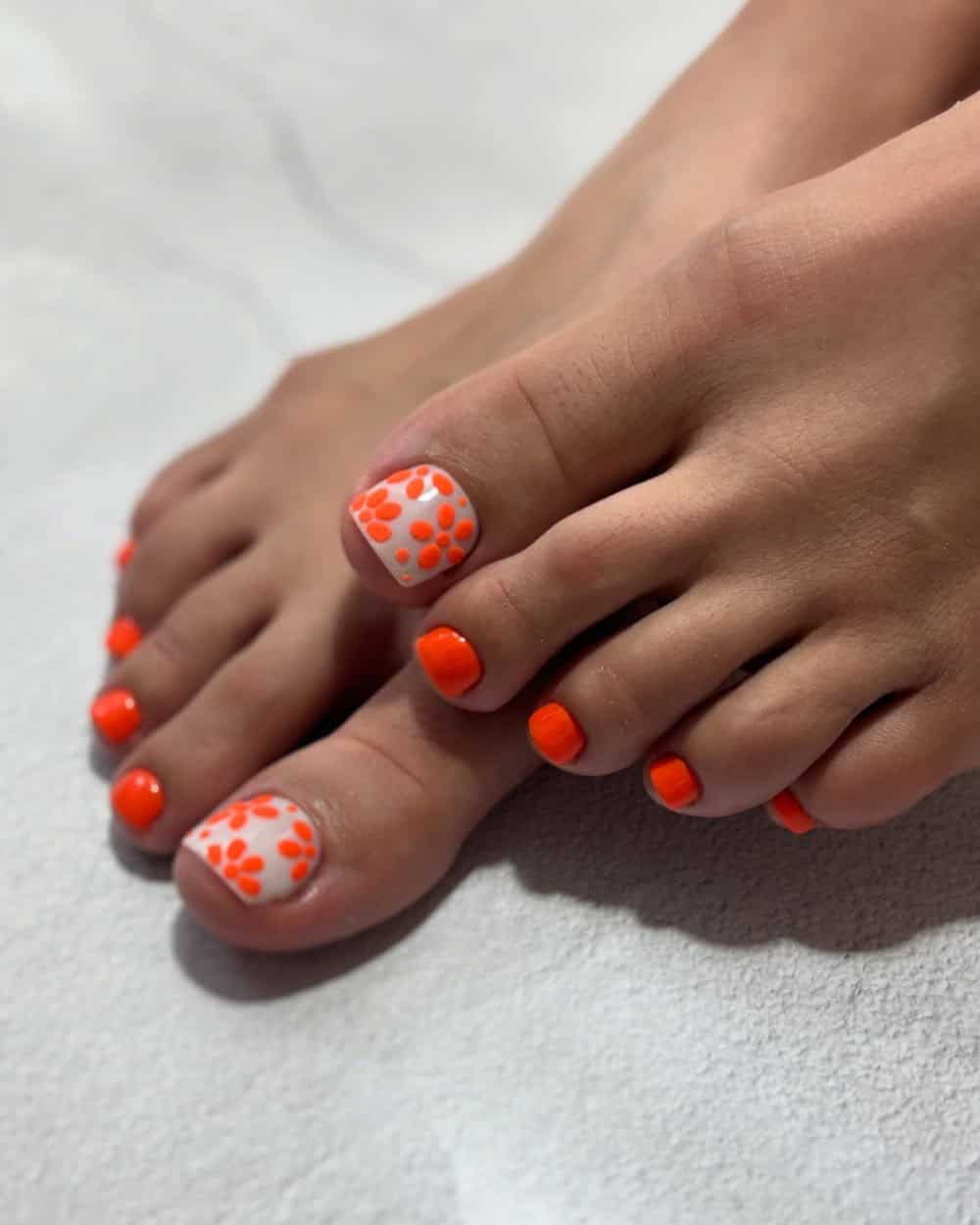 Orange toe nails with white floral patterns