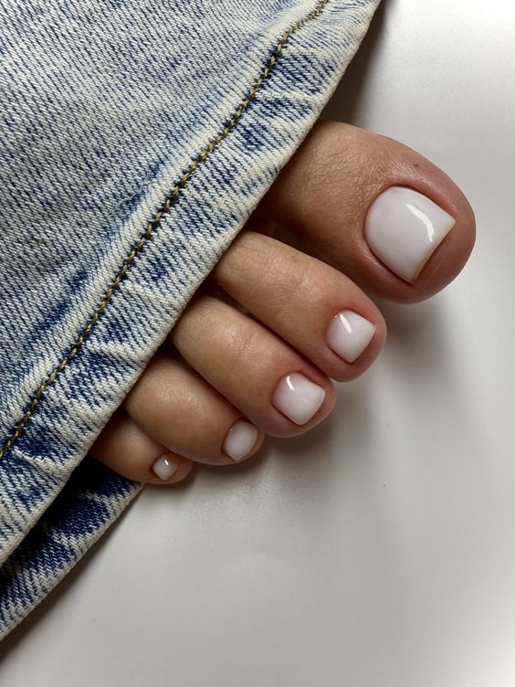 Glossy white toe nails with a refined appearance