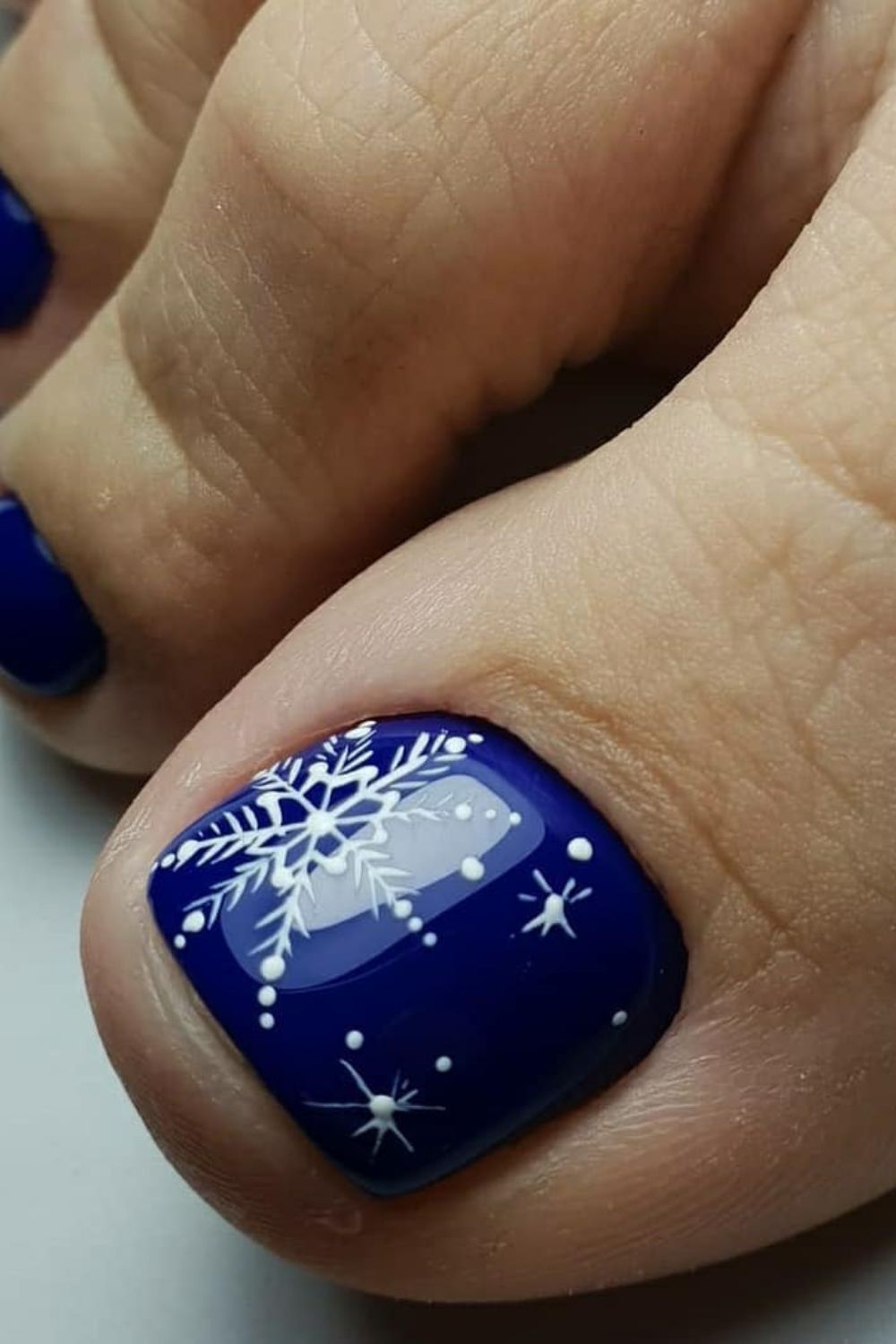 Dark blue toe nails with white snowflake patterns