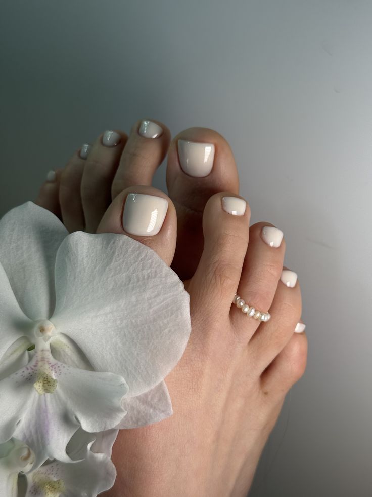 Ivory toe nails with a glossy finish and pearl accents