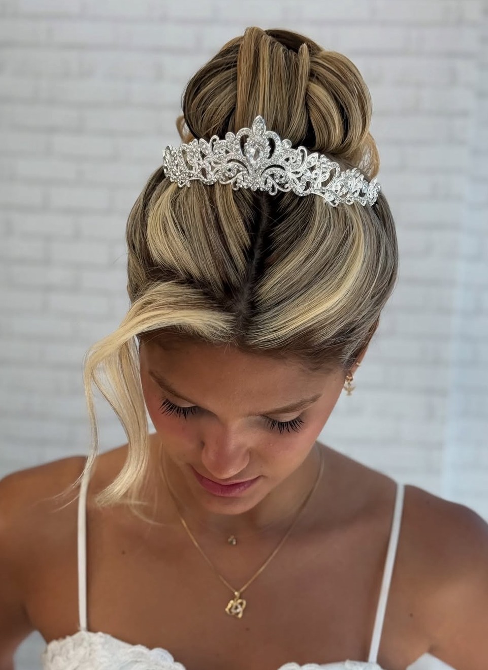 Regal high bun with tiara and sleek finish